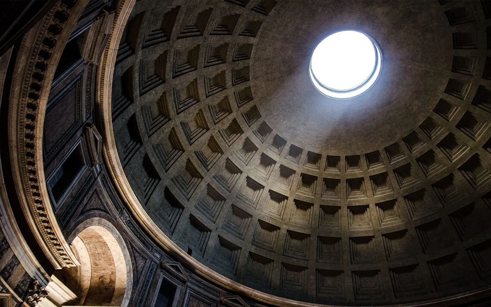 El óculo del Panteón de Roma visto desde dentro, con el haz de luz atravesando la cúpula de casetones.